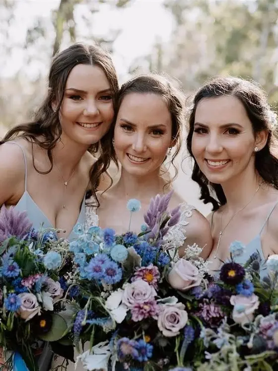 Three bridesmaids with wildflower bouquets and soft, natural glam