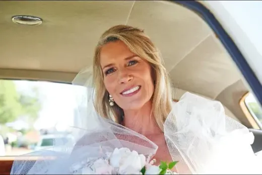 Bride with a veil in a wedding car — radiant makeup for mature skin